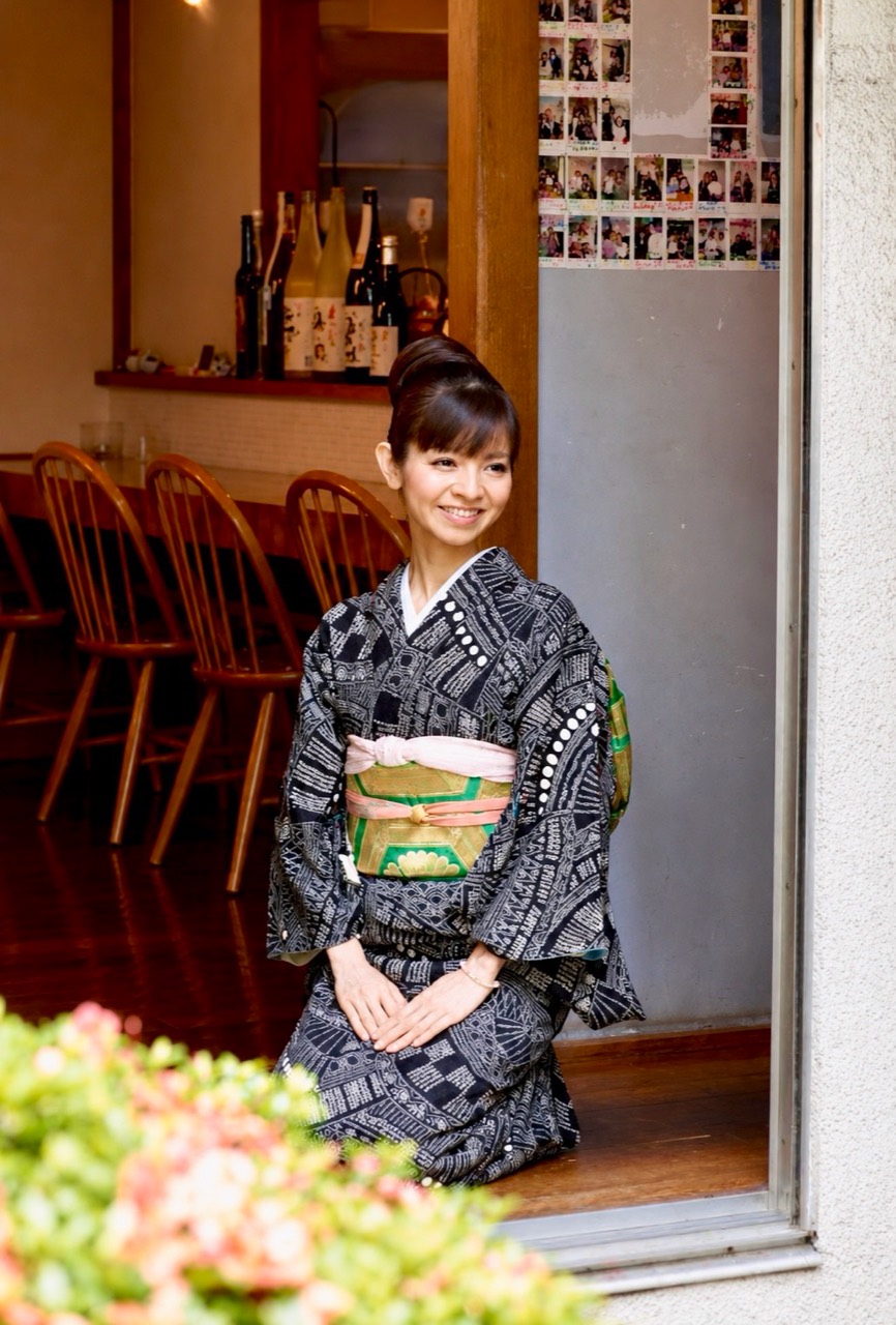 飲食店の入口に着物姿で座る園山真希絵